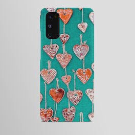 Red, handmade ceramic hearts suspended on hemp strings on a green background. Android Case