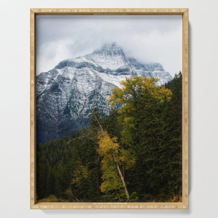 Transitions - Snowy Mountain Peak Overlooking Trees with Fall Color on Autumn Day in Glacier National Park Montana Serving Tray
