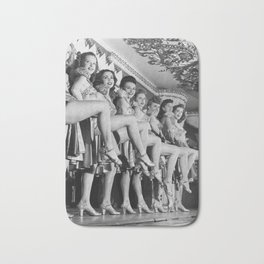Chorus line of women with legs lifted Bath Mat