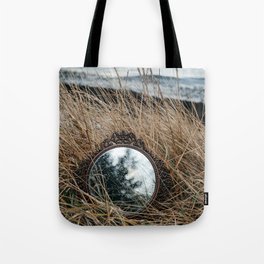 Vintage mirror on seaside reflects forest and sky. Tote Bag